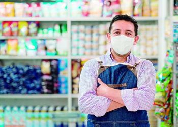 Business owner working at a grocery store wearing a facemask to avoid the coronavirus - pandemic lifestyle concepts